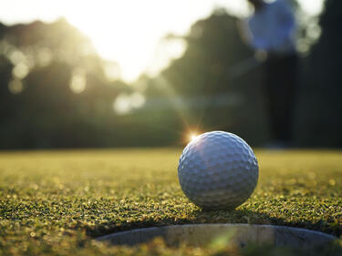White golf ball near hole on green grass