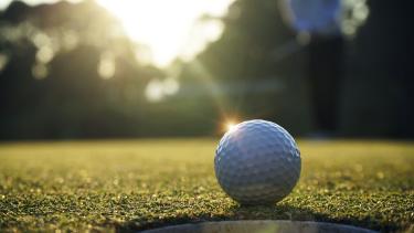 White golf ball near hole on green grass